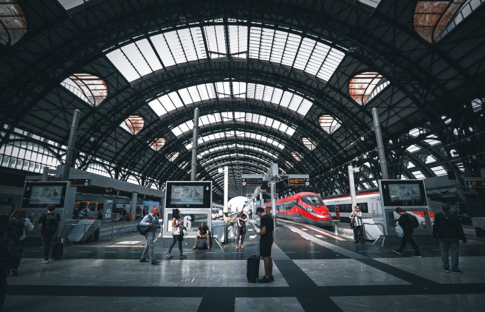 Commuters at Milano Central Station featuring modern trains under the iconic arched roof.