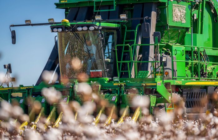 Close-up of a green cotton harvester operating in a field, capturing the machinery in detail.