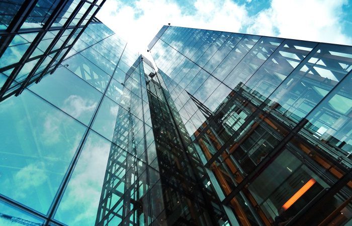 A striking view of a modern glass skyscraper reflecting the sky and clouds.
