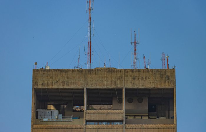 A rooftop in New Delhi features prominent antennas and a clear blue sky.