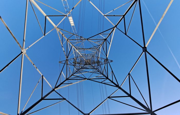 Stunning upward view of a geometric metal tower against a blue sky.