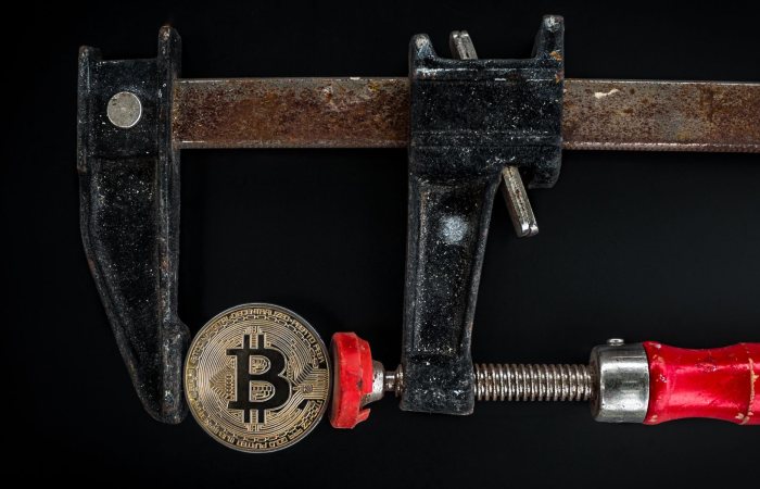 Conceptual image of cryptocurrency represented by a Bitcoin secured in a rusty clamp.